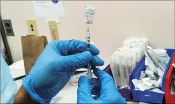  ?? AP PHOTO/MARY ALTAFFER ?? In this Feb. 18 file photo, a pharmacist prepares a syringe with Pfizer’s vaccine at a COVID-19 vaccinatio­n site in New York.