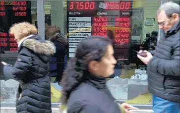  ?? Eitan Abramovich AFP/Getty Images ?? EXCHANGE rates are displayed in Buenos Aires on Friday, when the weakening Argentine peso rose slightly.