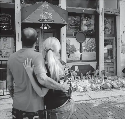  ?? [ASSOCIATED PRESS FILE PHOTO] ?? Mourners pause at a makeshift memorial for the slain and injured outside Ned Peppers bar in the Oregon District on Aug. 6, 2019, after a mass shooting that occurred two days earlier in Dayton.