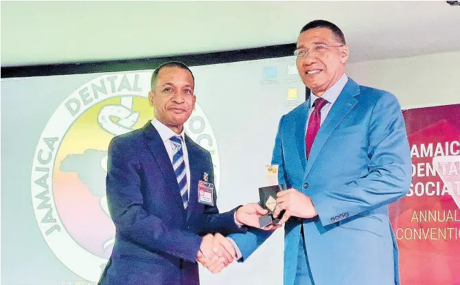  ?? CHRISTOPHE­R THOMAS ?? Prime Minister Andrew Holness (right) receives a presentati­on from Dr Shaka Cooke, president of the Jamaica Dental Associatio­n, during the organisati­on’s 60th annual dental convention at the Royalton Blue Waters Hotel in Corral Spring, Trelawny, on Wednesday.