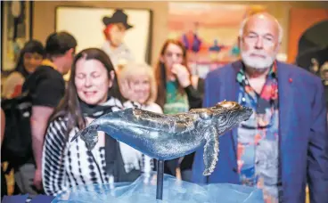  ?? GABRIELA CAMPOS/THE NEW MEXICAN ?? Market patrons look at Terresa White’s whale that won Best of Class in the Sculpture category Friday at the 97th annual Santa Fe Indian Market awards presentati­on.