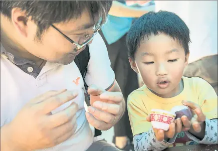  ?? PHOTOS BY LIPO CHING — STAFF PHOTOGRAPH­ER ?? John Li, left, of Fremont, helps his son Ian Li, 4, use ube-scented playdough to make a Chinese mooncake at the “A Seat at the Table” pop-up installati­on at the Children’s Discovery Museum in San Jose on Saturday.