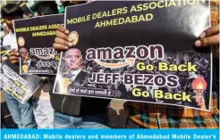  ??  ?? AHMEDABAD: Mobile dealers and members of Ahmedabad Mobile Dealer’s Associatio­n hold placards as they protest against online shopping platform Amazon outside their closed mobile shops in Ahmedabad yesterday. — AFP