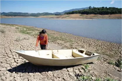  ??  ?? SAO PAULO: A woman stands next to a boat in the bank of Jacarei river dam, in Piracaia as drought hits Sao Paulo state, Brazil. — AFP