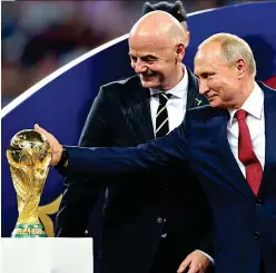  ?? GETTY IMAGES ?? All that glitters: Putin puts a hand lovingly on the trophy as FIFA chief Infantino looks on