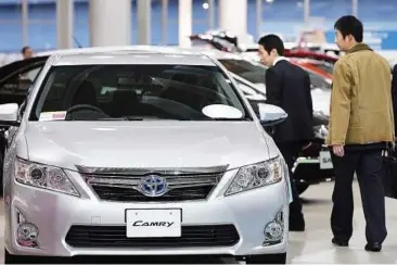  ??  ?? Visitors walk past a Toyota Camry vehicle at the company’s showroom in Tokyo. The latest figures confirm Toyota regained the global sales title. — EPA