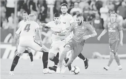  ?? — Gambar Reuters ?? DIKAWAL KETAT: Benzema (kanan) diasak hebat oleh dua pemain Sevilla ketika beraksi pada perlawanan La Liga di Stadium Ramon Sanchez Pizjuan, Seville Rabu lepas.