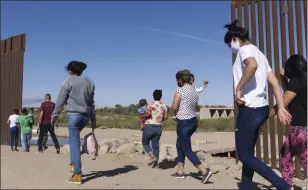  ?? EUGENE GARCIA — THE ASSOCIATED PRESS ?? A group of Brazilian migrants make their way around a gap in the U.S.-Mexico border in Yuma, Ariz., seeking asylum in the United States after crossing over from Mexico, in June 2021.