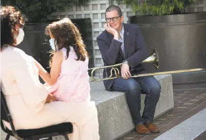  ?? Photos by Liz Hafalia / The Chronicle ?? S.F. Symphony principal trombone Tim Higgins talks to Maryam Ghajar and her daughter before playing for them.