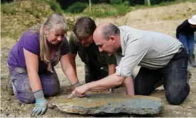  ?? Andrew Matthews/PA ?? Sally Hollingwor­th (left) with her husband Neville (centre) and Dr Tim Ewin from the Natural History Museum as they inspect a slab during the dig in the north Cotswolds. Photograph: