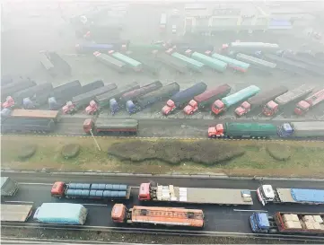  ??  ?? Trucks are seen stranded near a highway during a polluted day in Shijiazhua­ng, Hebei province, China. — Reuters photo