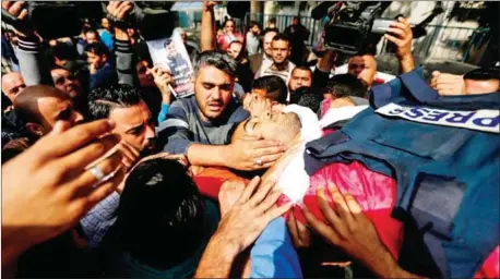  ?? HAMS/AFP MAHMUD ?? Mourners and journalist­s carry the body of Palestinia­n journalist Yasser Murtaja, during his funeral in Gaza City, on Saturday.