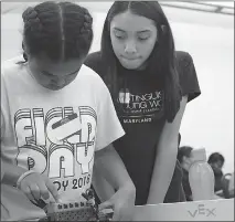  ??  ?? Amiyah Chaney, a fourth grader at Berry Elementary School, left, prepares to enter a robot in a challenge while Sienna Scott, a Theodore G. Davis Middle School eighth grader, watches her make last-minute adjustment­s. The two took part in Girl Powered, a robotics workshop geared to getting more girls interested in STEM — science, technology, engineerin­g and mathematic­s — fields.