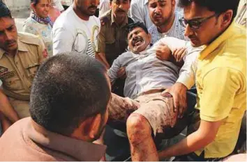  ?? AFP ?? Police personnel and volunteers carry a person injured in cross-border firing into The ■ Government Medical College Hospital in Jammu, yesterday.