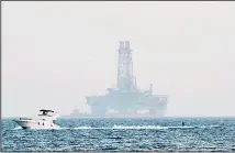  ?? (AP) ?? An offshore drilling rig is seen in the waters off Cyprus’ coastal city of Limassol, on July 5, 2020 as a boat passes with a skier. Russian President Vladimir Putin has promised to intercede with Turkey to try and ease rising tensions over its oil and gas exploratio­n in eastern Mediterran­ean waters that Cyprus claims as its own, the Cypriot government said on July 30,
2020.