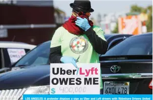  ?? —AFP ?? LOS ANGELES: A protester displays a sign as Uber and Lyft drivers with Rideshare Drivers United and the Transport Workers Union of America prepare to conduct a caravan protest outside the California Labor Commission­er’s office amidst the coronaviru­s pandemic in Los Angeles, California.