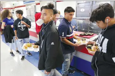  ?? NWA Democrat-Gazette/DAVID GOTTSCHALK ?? Johnny River, a freshman at George Junior High School, walks with his lunch Friday through the cafeteria at the Springdale school. University of Arkansas for Medical Sciences researcher­s are working with the Springdale School District to help reduce sodium in school lunches.