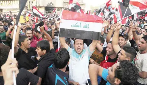  ??  ?? BAGHDAD: Protesters chant in support of Iraqi Prime Minister Haider al-Abadi as they carry national flags during a demonstrat­ion in Tahrir Square in Baghdad, Iraq, yesterday. Friday’s protesters were joined for the first time by followers of Muqtada...