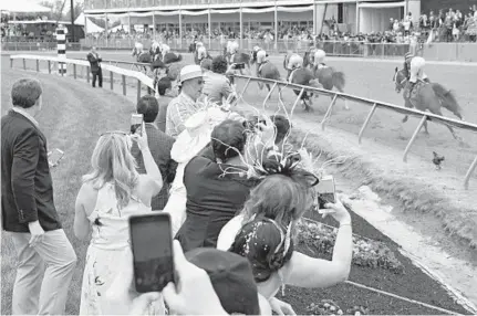  ?? KARL MERTON FERRON/BALTIMORE SUN ?? Spectators get a close-up experience as the field of 10 horses head into turn one during the 2017 Preakness Stakes at Pimlico Race Course, with Cloud Computing ultimately taking first place.