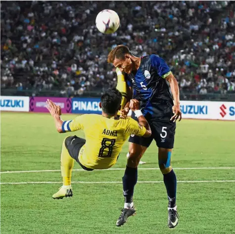  ??  ?? Going all out: Cambodia defender Soeuy Visal (right) vying for the ball with Malaysia striker Zaquan Adha Abdul Razak during the AFF Suzuki Cup match at the Olympic Stadium in Phnom Penh on Thursday. — AFP