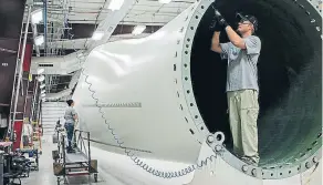  ??  ?? Instalació­n de piezas en la base de una turbina eólica en una factoría de Siemens