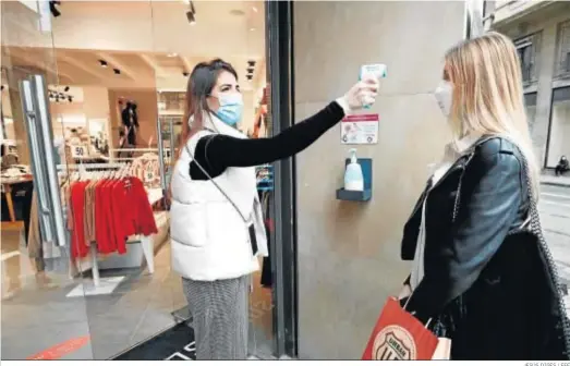  ?? JESÚS DIGES / EFE ?? Una encargada de una tienda en Pamplona toma la temperatur­a a una de las trabajador­as antes de entrar al comercio.