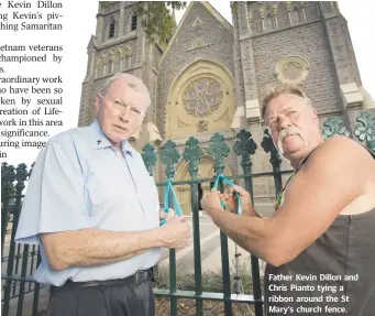  ??  ?? Father Kevin Dillon and Chris Pianto tying a ribbon around the St Mary's church fence.