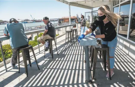  ?? Photos by Nick Otto / Special to The Chronicle ?? Megan Keeton (right) sterilizes the patio furniture at the Mare Island Brewing Co. Ferry Taproom in Vallejo.