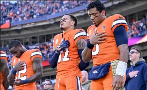  ?? AARON ONTIVEROZ — THE DENVER POST ?? Kareem Jackson,left, Justin Simmons, center, and Russell Wilson of the Denver Broncos stand for the national anthem before the game against the Las Vegas Raiders at Empower Field at Mile High on Nov. 20.