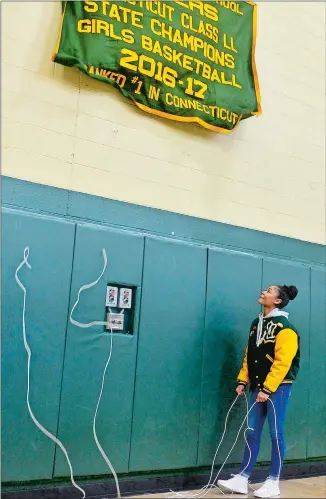  ?? SARAH GORDON/THE DAY DAY ?? Former New London all-state guard Jada Lucas smiles after unveiling the Whalers’ 2016-17 Class LL state championsh­ip banner before Saturday’s 74-25 girls’ basketball win over Torrington on Saturday.