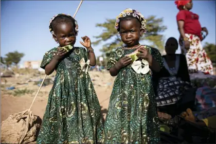  ?? SOPHIE GARCIA — THE ASSOCIATED PRESS ?? Twins eat slices of watermelon Thursday Nov. 25, 2021at the Patte d’Oie district of Ouagadougo­u, Burkina Faso, where mothers of twins come to beg on the road. In Burkina Faso, a country with a strong belief in the supernatur­al, twins are regarded as children of spirits whose mothers were specially selected to bear them.