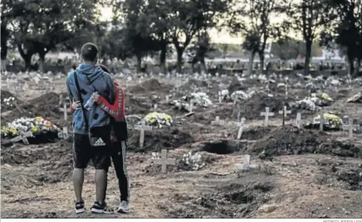  ?? ANTONIO LACERDA / EFE ?? Un hombre abraza a una mujer en el cementerio de Caju, en la zona norte de Río de Janeiro.