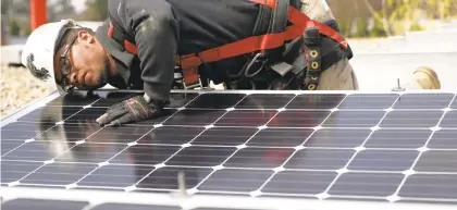  ?? STACEY WESCOTT/CHICAGO TRIBUNE ?? A worker installs a solar panel on the roof of a business in Elgin, Illinois.