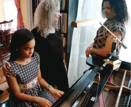  ?? BEBETO MATTHEWS/AP ?? Julie Wegener, centre, a music teacher with the MusicLink Foundation, her student Anmy Paulino Collado, left, and Anmy’s mom, Andolina Collado, as they finish a music session, in New York.