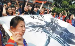  ?? DAMIR SAGOLJ / REUTERS ?? Supporters hold a banner bearing the image of soccer player Cheick Tiote during a memorial service in Beijing on Tuesday.