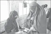  ??  ?? A woman voter’s finger is scanned before casting during parliament­ary elections in Kandahar on Saturday.