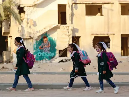  ?? AFP ?? Palestinia­n children walk past a damaged building in Gaza City on their way to school on Monday. The building was destroyed in Israeli raids.