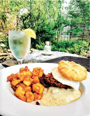  ?? PHOTOS BY ANNE BRALY ?? Take a seat in the garden for a delicious breakfast, lunch, dinner or weekend brunch at The Looking Glass. The menu features homemade biscuits served in various ways, such as a Nashville Hot Chicken Biscuit served with crispy potatoes.