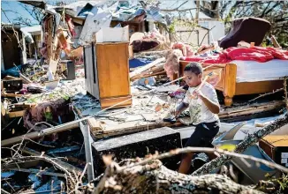  ?? EMILY KASK / THE NEW YORK TIMES ?? Romark Davis, 7, walks through the wreckage of the mobile home park where he lives in Panama City, Fla., on Friday. Hurricane Michael’s death toll rose to 16 on Friday and was expected to climb higher as emergency workers searched rubble left by the Category 4 storm.