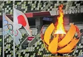  ??  ?? Left: The Olympic flame burns alongisde the Japanese and Olympic flags at the Stadium.