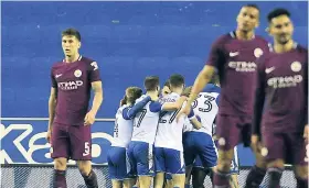  ??  ?? Wigan’s Will Grigg celebrates with his teammates after scoring his side’s opening goal during their English FA Cup fifth-round match against Manchester City at The DW Stadium, Wigan, England, yesterday.