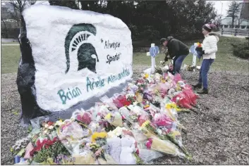  ?? PAUL SANCYA/AP ?? MOURNERS LEAVE FLOWERS AT THE ROCK Lansing, Mich., on Wednesday. on the grounds of Michigan State University in East