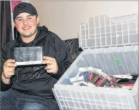  ?? NIKKI SULLIVAN/SALTWIRE NETWORK ?? Jayden Green, 16, sits in the living room of his Glace Bay home holding one of the android boxes he is selling through his business JayG Electronic­s. Beside him is a box of cellphone cases and accessorie­s, Green’s second biggest seller next to the boxes which he sells online and locally.