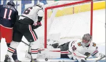  ?? JAY LAPRETE/AP ?? Blackhawks goalie Malcolm Subban makes a save as teammate Nikita Zadorov, center, and the Blue Jackets’ Kevin Stenlund battle for the rebound during the third period on Thursday.