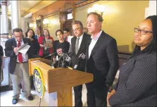  ?? Susan Haigh / Associated Press ?? Gov. Ned Lamont, center, speaks to reporters at the state Capitol following a closeddoor meeting with state lawmakers about electronic tolls on June 19 in Hartford. Lamont says he still hopes to hold a vote on tolls in a special legislativ­e session, despite resistance from some lawmakers.