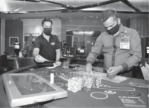  ?? PAUL W. GILLESPIE/BALTIMORE SUN MEDIA ?? Table games pit manager Pragnesh Patel, left, oversees dealer supervisor Panthall Khlas as he loads chips into a blackjack table at Live! Casino & Hotel.