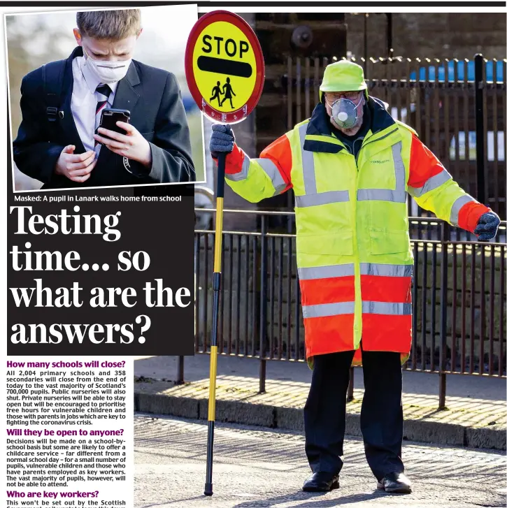  ??  ?? Putting safety first: A masked lollipop man on duty in Stockbridg­e, Edinburgh, was clearly taking no chances yesterday