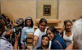 ??  ?? Des visiteurs se font photograph­ier devant La Joconde au Louvre.
