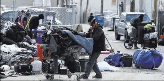  ?? DAVID ZALUBOWSKI/THE ASSOCIATED PRESS ?? Homeless people clear their belongings March 8 from a camp as city officials warned that the homeless had to move from their makeshift structures along the sidewalks in the area, near the Denver Rescue Mission in downtown Denver.