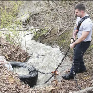  ?? Brodie Johnson • Times-Herald ?? The Forrest City fire and public works department­s worked together this morning to clear a drain culvert in the Edgewood subdivisio­n. Troy Thweatt, a captain with the FCFD, pulls a tire out of the culvert after the pipe had been cleared.